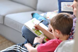 Preschool boy sits with father reading a book.