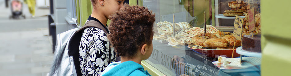 Two kids outside f a store looking at different foods